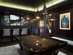 a pool table in the middle of a room with chairs and bar lights on either side