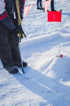 people are playing golf in the snow on a sunny day with flags and poles sticking out of the snow