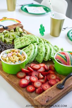 a wooden cutting board topped with fruit and veggies on top of a table