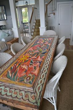 an ornately decorated table in the middle of a living room with white wicker chairs