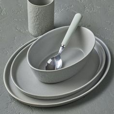 a set of three white dishes with silver spoons