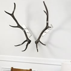 two antlers mounted to the side of a wall next to a chair and lamp