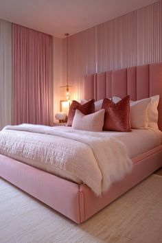 a bedroom with pink and white bedding, pillows and lamps on the nightstands