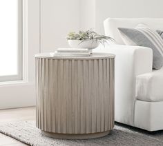 a white couch sitting next to a table with a potted plant on top of it