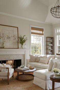 a living room filled with furniture and a fire place under a chandelier in front of a window