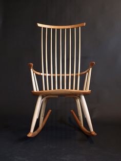 a wooden rocking chair with white paint on the back and arms, against a black background