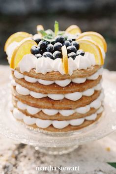 a layered cake with lemons, blueberries and orange slices