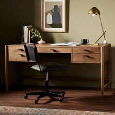 a desk with a chair, lamp and pictures on the wall in front of it