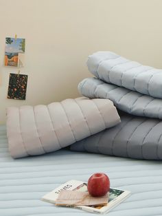 a stack of pillows and an apple on a bed