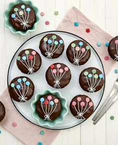 a plate with chocolates decorated with flowers and balloons on it next to a spoon