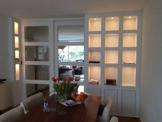 a dining room table with flowers in a vase on it and some bookshelves