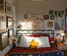 a bedroom with many pictures on the wall and a teddy bear sitting on the bed