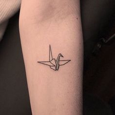 a small origami bird tattoo on the arm