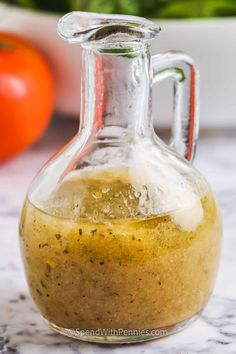 a glass bottle filled with mustard sitting on top of a counter next to tomatoes and basil