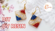 two square shaped earrings with red, white and blue glitters on them next to pink flowers