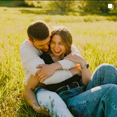 two people sitting in the grass hugging each other