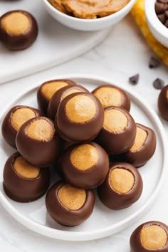 chocolate covered peanut butter balls on a white plate next to other desserts and bowls