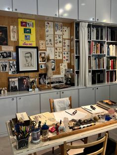 a room with many bookshelves and pictures on the wall, including an office desk