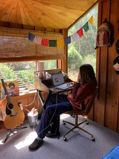 a woman sitting at a desk in front of a laptop computer on top of a wooden table