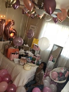 a woman sitting at a table surrounded by balloons