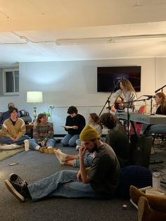 a group of people sitting on the floor in front of microphones and recording equipment