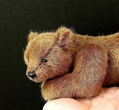 a small teddy bear sitting in the palm of someone's hand