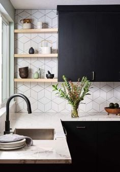 a kitchen with black cabinets and marble counter tops, an open shelving above the sink