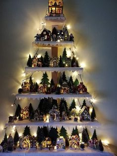 a christmas tree made out of shelves with lights on it and houses in the middle