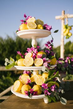 a three tiered cake stand with lemons and purple flowers on the bottom layer