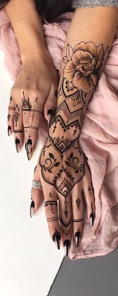 a woman is holding her hands with henna tattoos on it's arms and hand