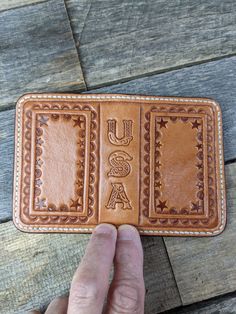 a hand holding up a leather wallet with the word usa on it's side