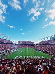 a football stadium filled with lots of people watching the game on a sunny day in red and white