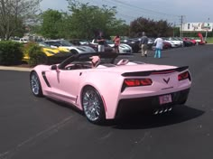 a pink convertible car parked in a parking lot