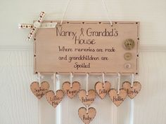 a wooden sign hanging from the side of a white wall with hearts attached to it