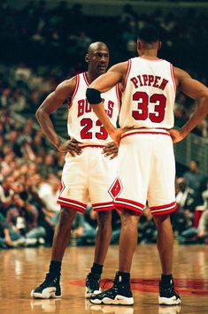 two basketball players standing next to each other in front of an audience at a game