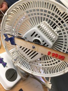 a white fan sitting on top of a wooden table