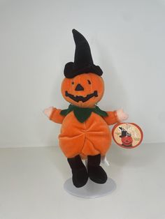 an orange stuffed pumpkin with a black hat and green scarf