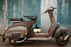 an old scooter is parked in front of a building with peeling paint on it