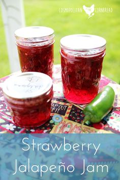 two jars of strawberry jalapeno jam sitting on top of a colorful table cloth