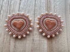 two pairs of pink and white beaded heart shaped earrings on wooden table with wood background