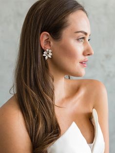 a woman with long brown hair wearing white dress and silver earring on her left ear