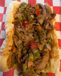 a close up of a hot dog with toppings on a paper tableclothed tray