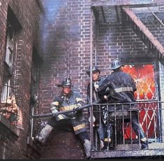 two fire fighters are on the balcony of a building