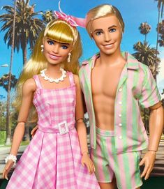 two barbie dolls standing next to each other in front of a palm tree filled background