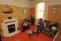 two people sitting on couches in a living room next to a fire place and fireplace