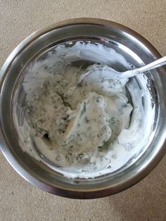 a metal bowl filled with white sauce on top of a floor