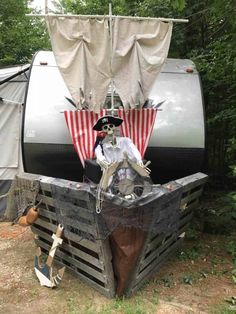 a pirate statue sitting on top of a wooden crate in front of a camper