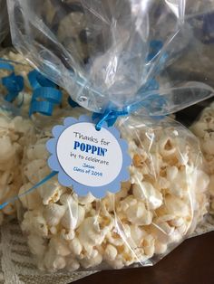 popcorn bags filled with white chocolate and blue ribbon tied around the bag are labeled thanks for poppin