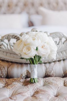 a bouquet of white flowers sitting on top of a bed next to a tray with pillows