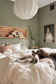 an unmade bed with white sheets and blankets on it, in a bedroom setting